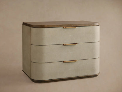 Charbon faux shagreen Harrow Nightstand with three bronze-handled drawers, next to a bed.
