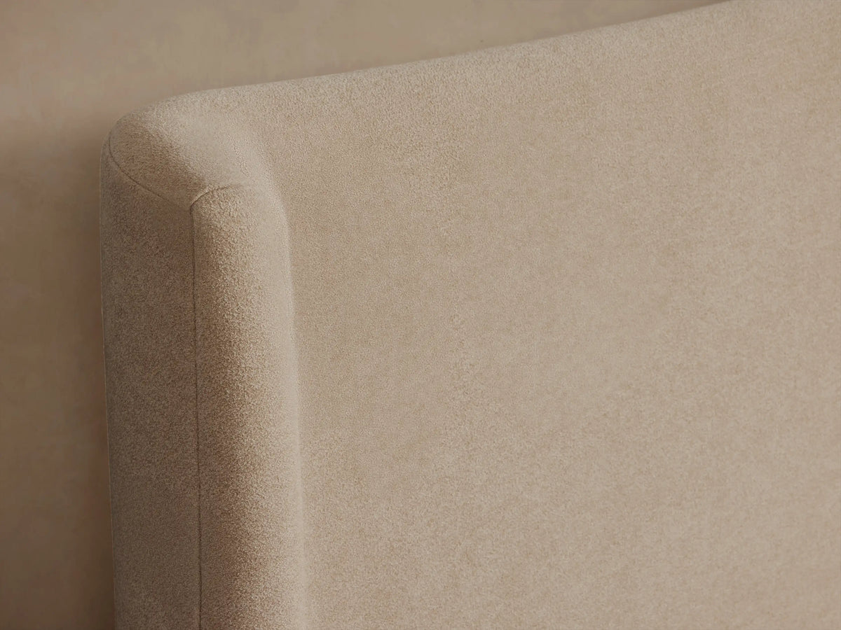 Side view of a beige Hathaway Bed. It features an upholstered frame, curved wing-back headboard, and white bedding with two pillows.