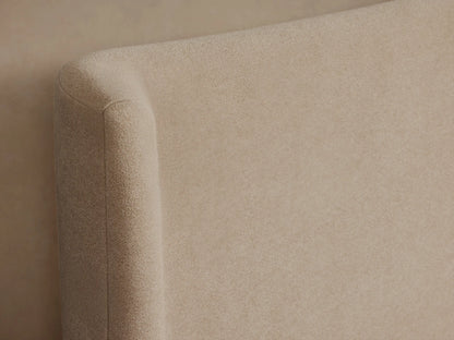 Side view of a beige Hathaway Bed. It features an upholstered frame, curved wing-back headboard, and white bedding with two pillows.