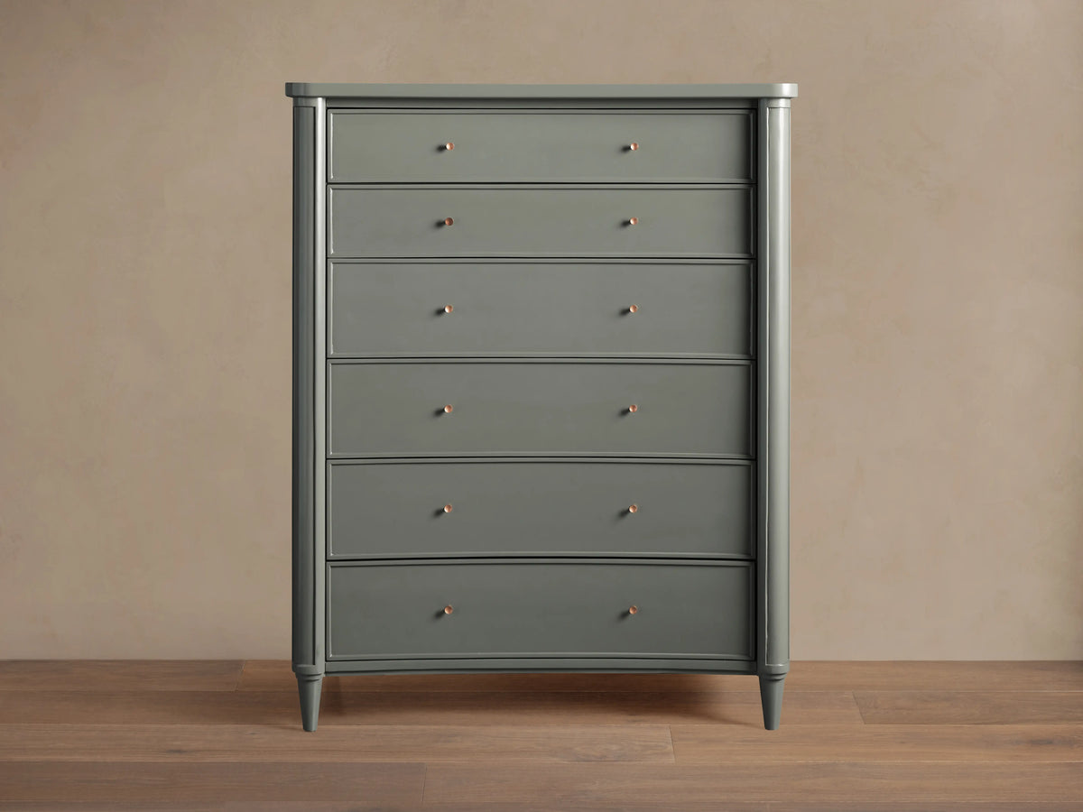 Henley Six-Drawer Dresser in gray finish, with petite brass pulls on each drawer, standing against a beige wall on wooden flooring.