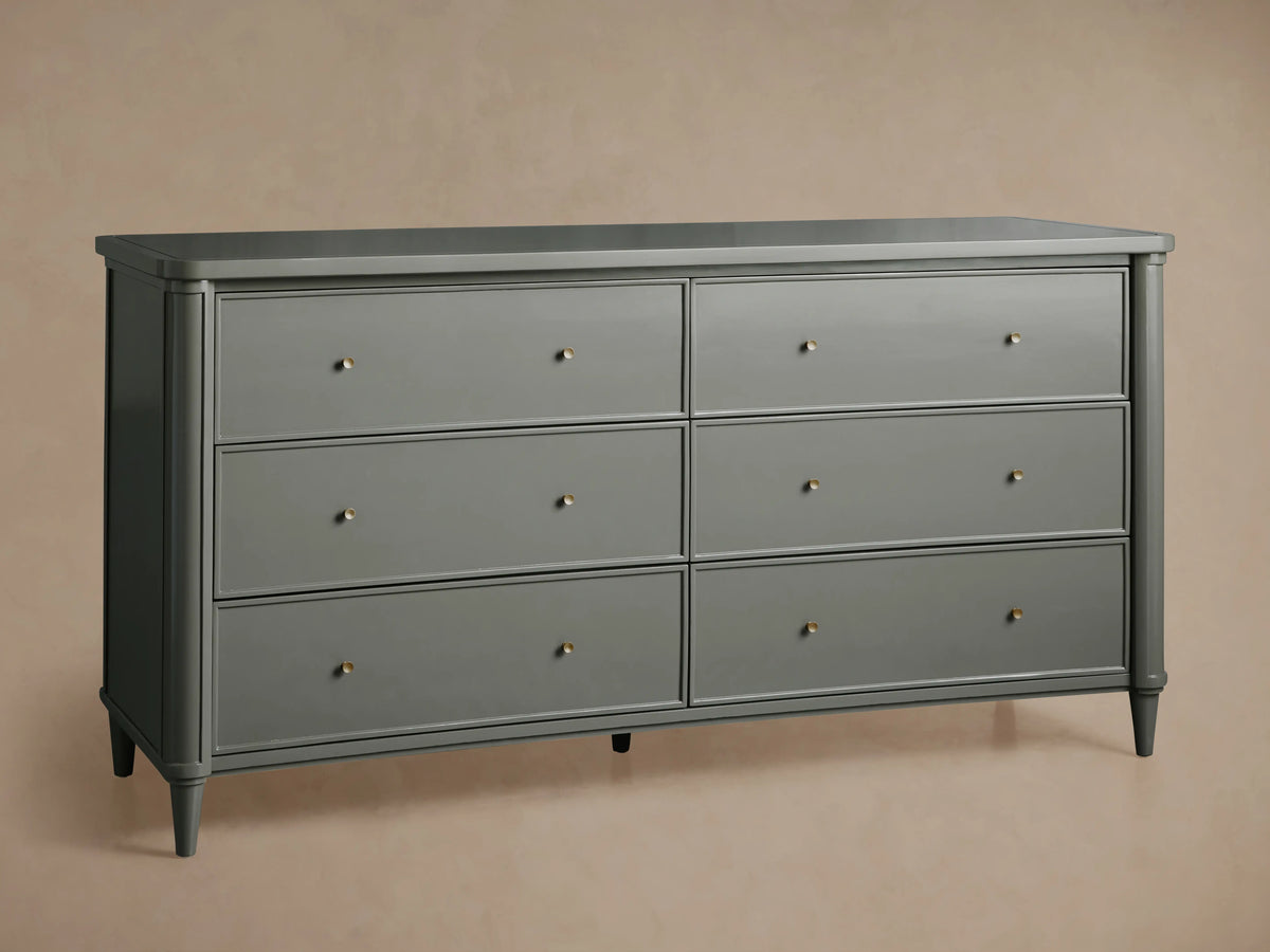 Left side view of the dark Henley Wide Six-Drawer Dresser, featuring six drawers with petite brass pulls, in a bedroom setting.