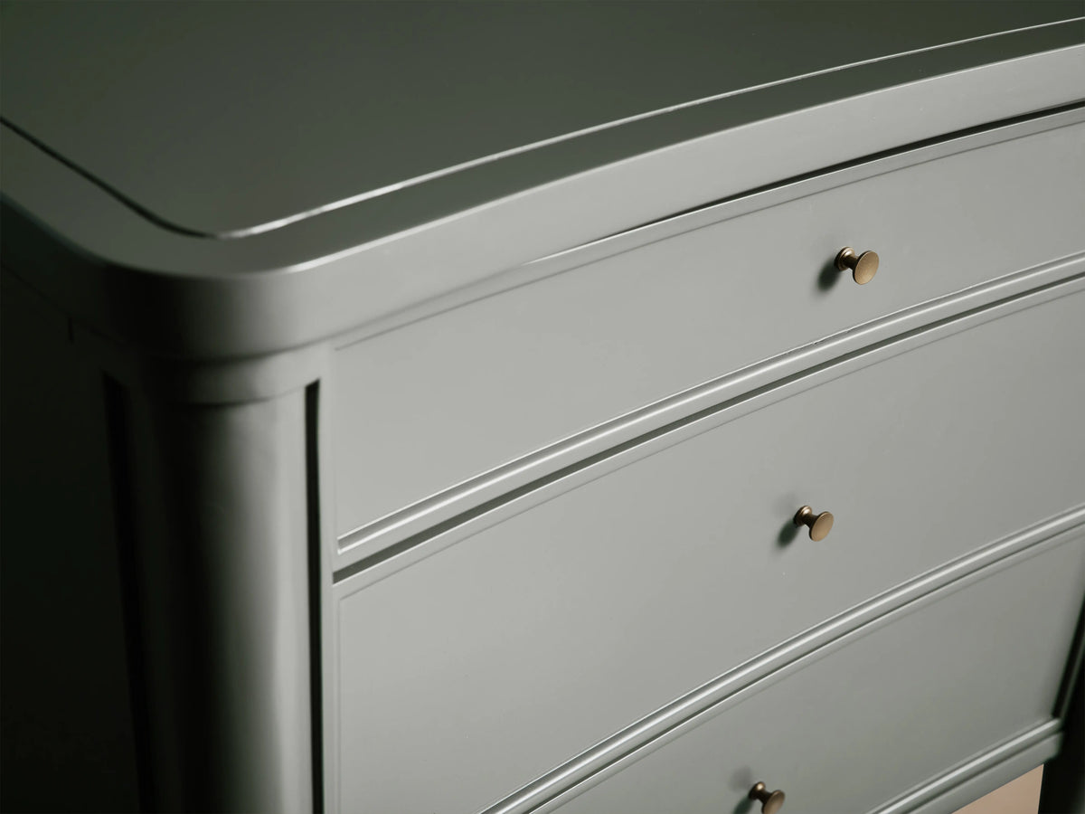 Henley Nightstand with a smooth, curved design in gray finish, featuring three drawers with petite brass pulls; elegant wood texture.