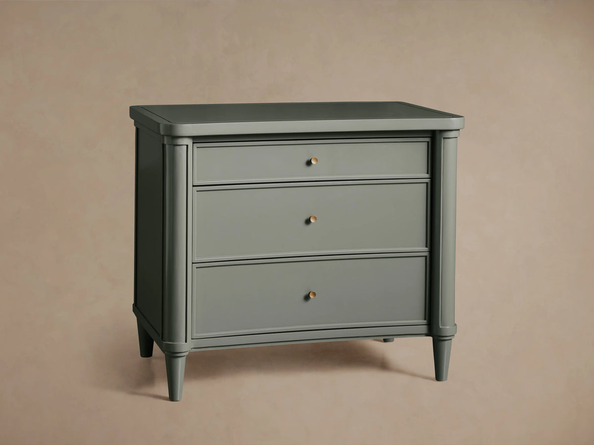 Henley Nightstand in gray with three drawers, featuring petite brass pulls, and a smooth lacquer finish.