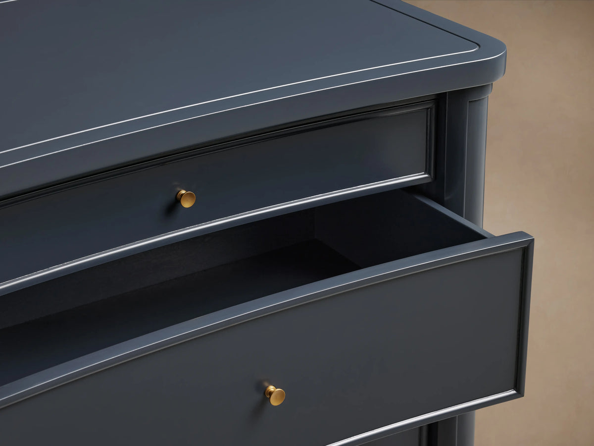 Henley Nightstand in dark navy. Three drawers with petite brass pulls; top closed, middle & bottom slightly open. Rounded top edge.