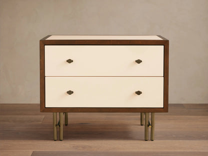 Henton Nightstand: dark wood frame, two cream high-gloss drawers with brass knobs, and sleek brass metal legs on wood floor.