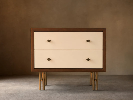 Henton Nightstand: dark wood frame, two cream high-gloss drawers with brass knobs, and sleek brass metal legs on wood floor.