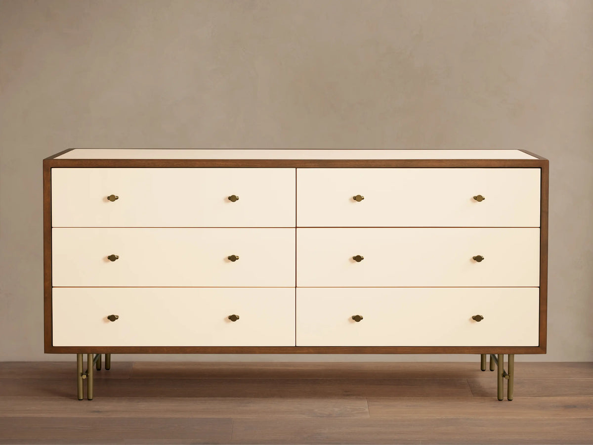 Henton Six-Drawer Dresser with cream drawers, dark wood frame, brass knobs, and brass-finished tubular legs.