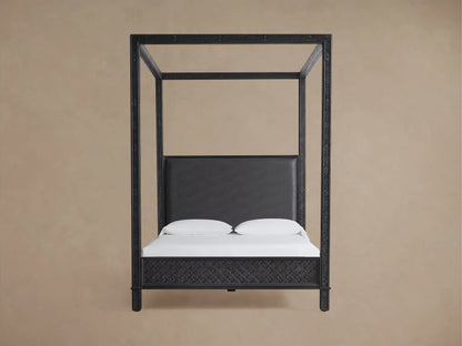 Keene Canopy Bed: Dark brown wooden frame with intricate patterns, brown leather headboard, and white bedding on wood floor.