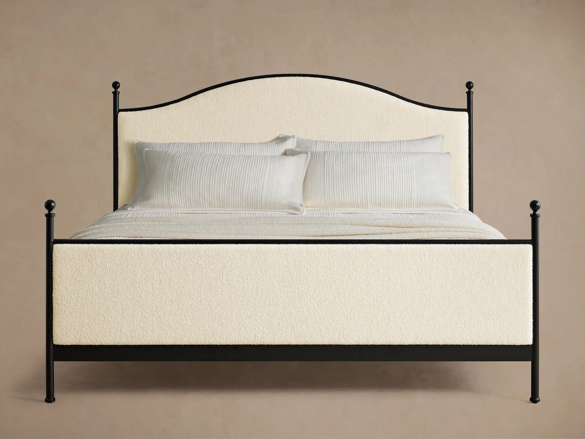 Close-up of the cream upholstered panel and black iron frame with finial detail of the Kimber Upholstered Bed.