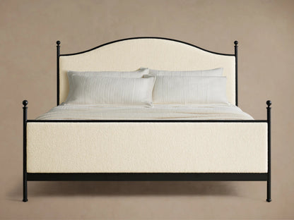 Close-up of the cream upholstered panel and black iron frame with finial detail of the Kimber Upholstered Bed.