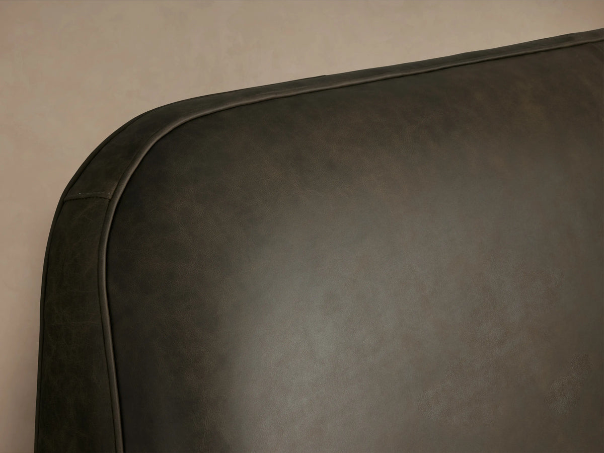 Front view of the dark brown Kinnan Leather Bed with a three-panel padded headboard and white bedding.
