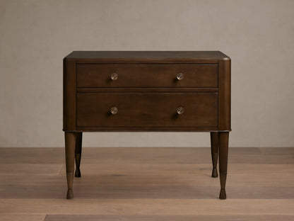Laurent Nightstand with dark wood finish, featuring two drawers with brass knobs and elegant tapered legs on a wooden floor.
