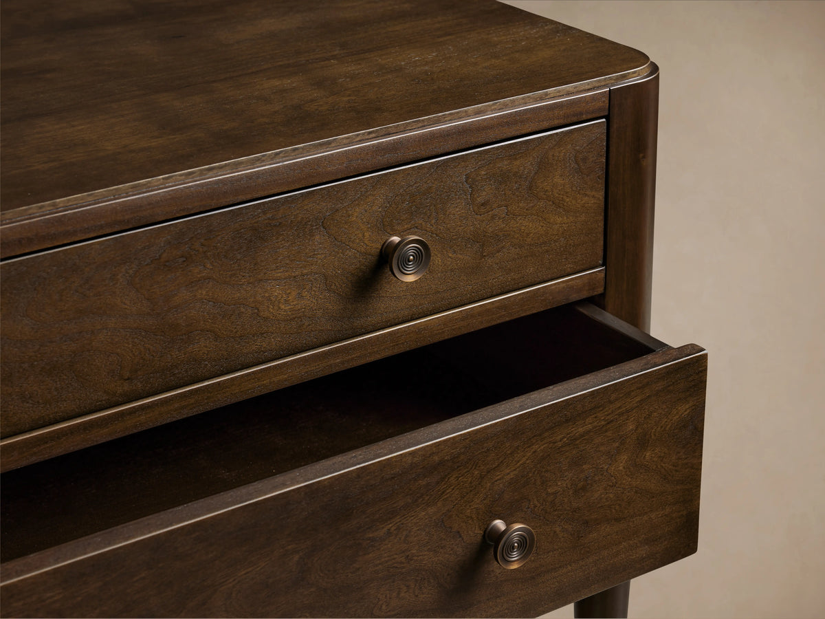 Laurent Nightstand in dark wood with two drawers. Top drawer closed, bottom drawer slightly open. Patinaed brass knobs visible.