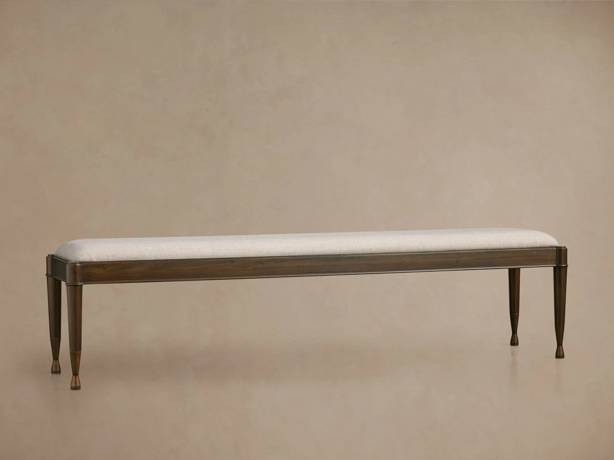 Laurent Bench with a sleek rectangular silhouette, solid wood frame, light upholstered seat, and patinaed brass feet.