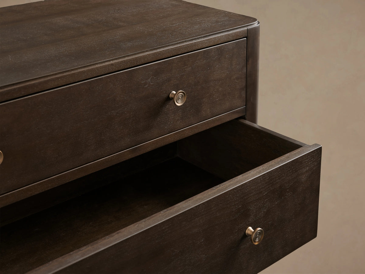 Laurent Five-Drawer Dresser made of dark mahogany and cherry veneers, features patinaed brass feet and knobs, in a neutral setting.