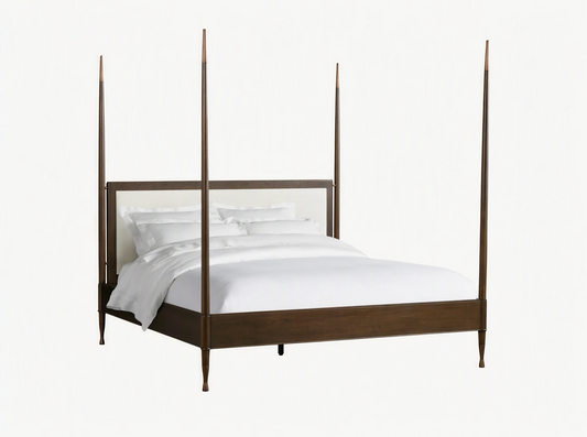 Four-poster Laurent Bed with mahogany wood frame and brass finials. White upholstered headboard, on wood floor in neutral room.