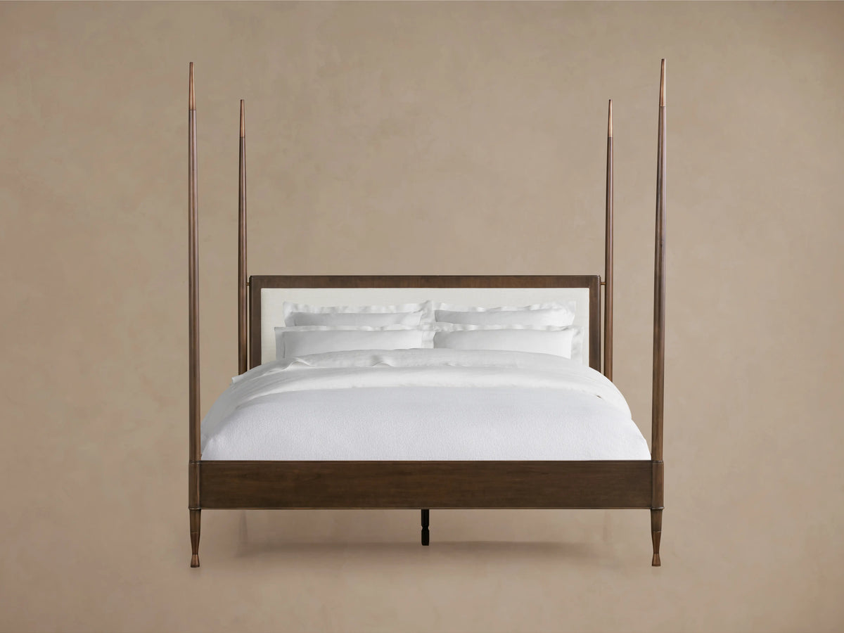 Four-poster Laurent Bed with solid mahogany wood frame, white upholstered headboard, and white bedding against a neutral background.