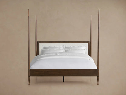 Four-poster Laurent Bed with solid mahogany wood frame, white upholstered headboard, and white bedding against a neutral background.