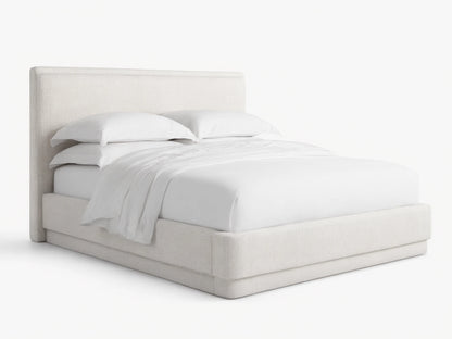 Light cream textured fabric upholstered Lennon Bed with matching headboard and frame, dressed with white bedding, on a wood floor.