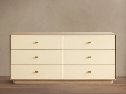 Front view of the cream Lowen Six-Drawer Dresser with light oak wood veneer frame, faux leather drawer fronts, and champagne brass pulls.