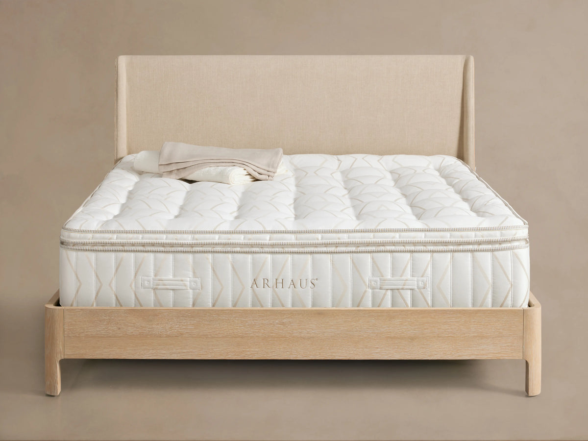 Luxury Plush Mattress on a wooden bed frame with a beige upholstered headboard, featuring a quilted, textured surface.