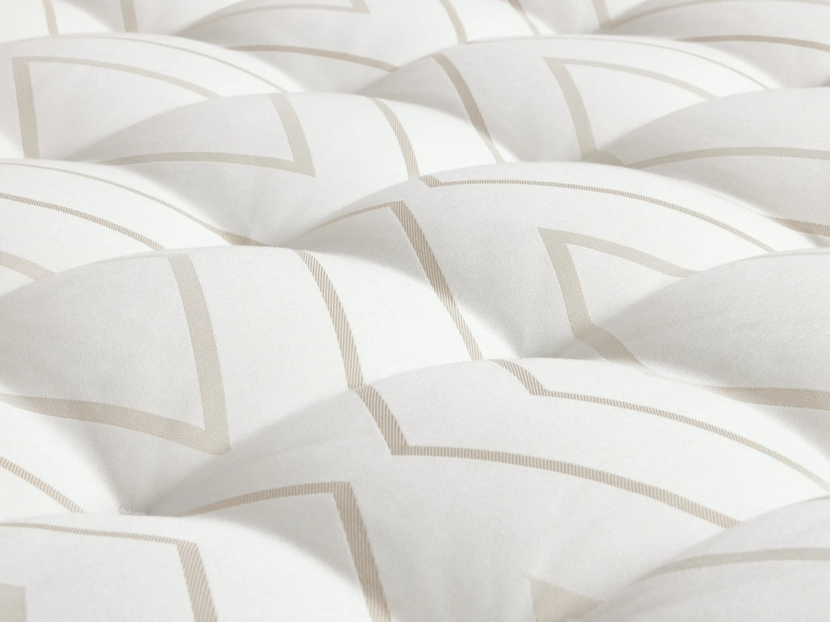 Luxury Plush Mattress on a light wood bed frame, featuring white quilted surface and embroidered handles, with a neatly placed throw blanket.