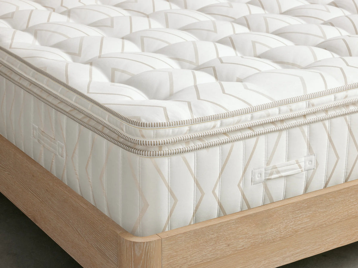 Luxury Plush Mattress close-up showing cream and beige striped fabric, featuring a small button-like tuft at the center.