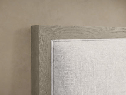 Malone Upholstered Bed with light neutral fabric headboard, wooden frame in grayish tone, close-up on corner detail.