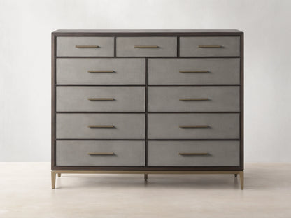 Malone Eleven-Drawer Dresser. Dark wood frame, light grey shagreen-textured drawers with gold handles, and brass base.