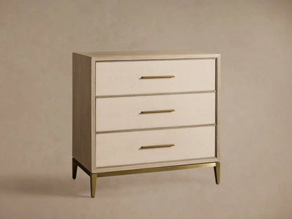 Malone Three-Drawer Chest. Light wood frame, textured bone drawer fronts with gold pulls. Top closed, middle and bottom partially open.