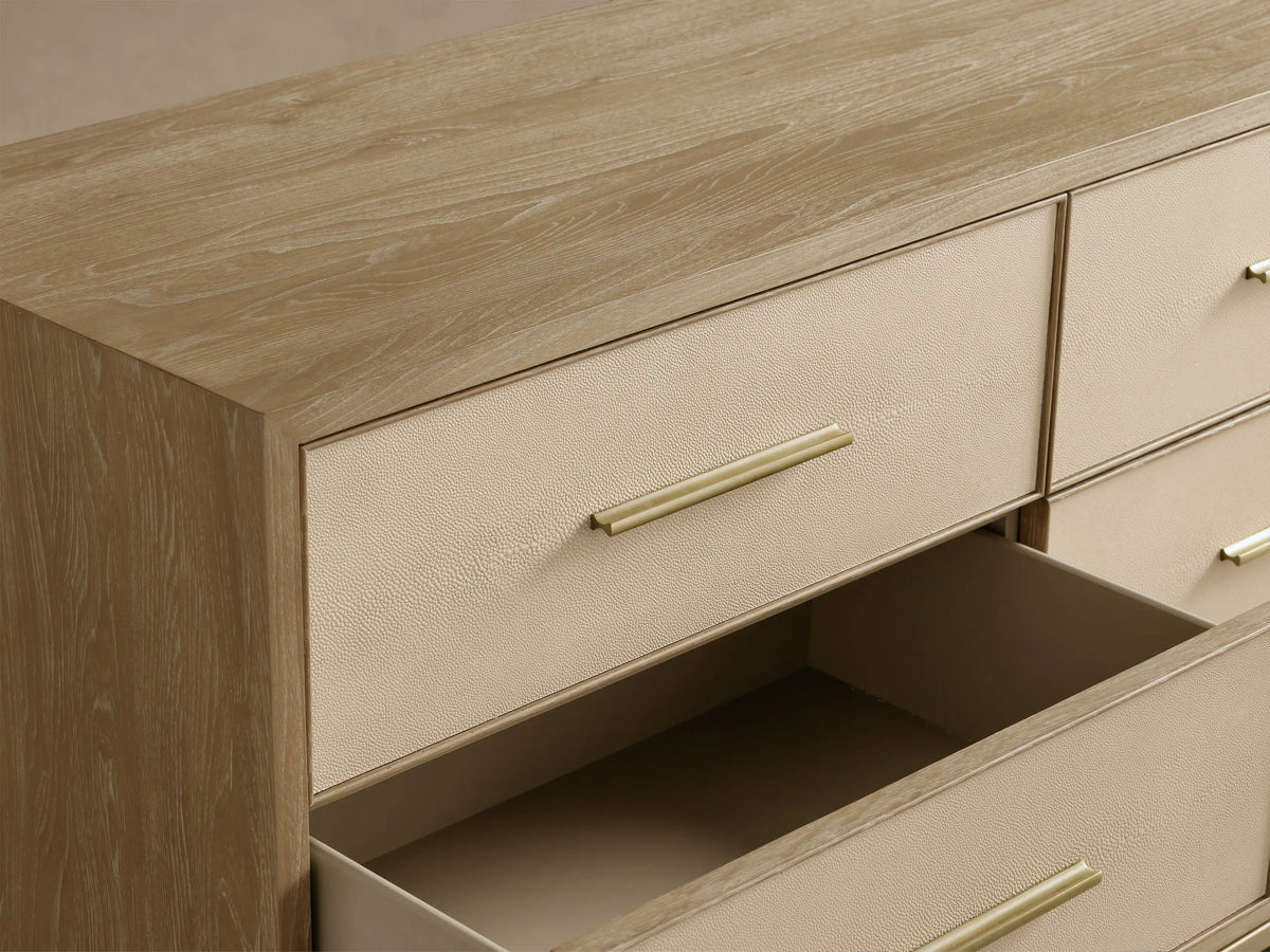 Close-up of the Bone Malone Nine-Drawer Dresser with light oak wood and textured bone shagreen drawer fronts with gold bar pulls. One drawer is open.