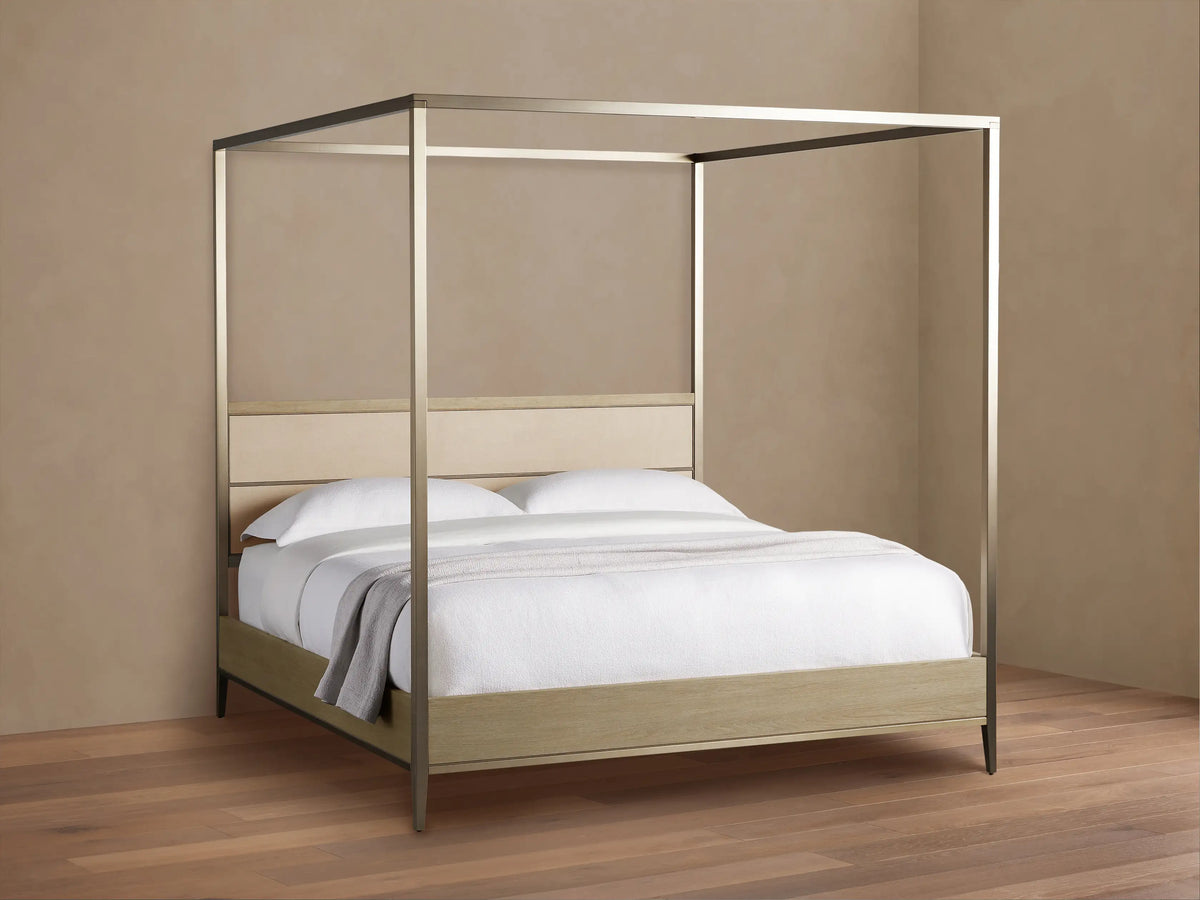 Front view of the Malone Canopy Bed, metallic gold frame, light oak base, cream leather headboard, white bedding, gray throw.