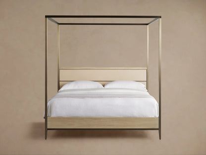 Front view of the Malone Canopy Bed, metallic gold frame, light oak base, cream leather headboard, white bedding, gray throw.