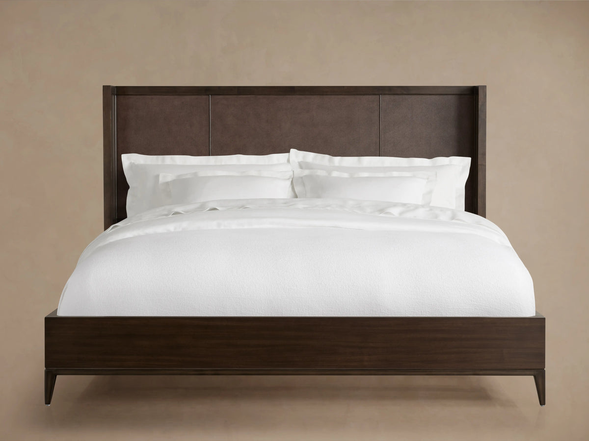 Malone Shelter Bed with a dark wood frame and rich brown leather headboard, dressed in crisp white bedding, shown front view.