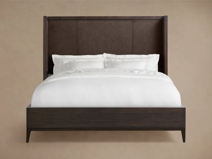 Malone Shelter Bed in dark wood with a high, panelled headboard featuring reconstituted leather insets, dressed in white bedding.