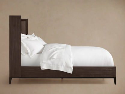 Close-up of dark wood bed frame corner with textured brown leather inset on one side, showcasing sleek design and craftsmanship.