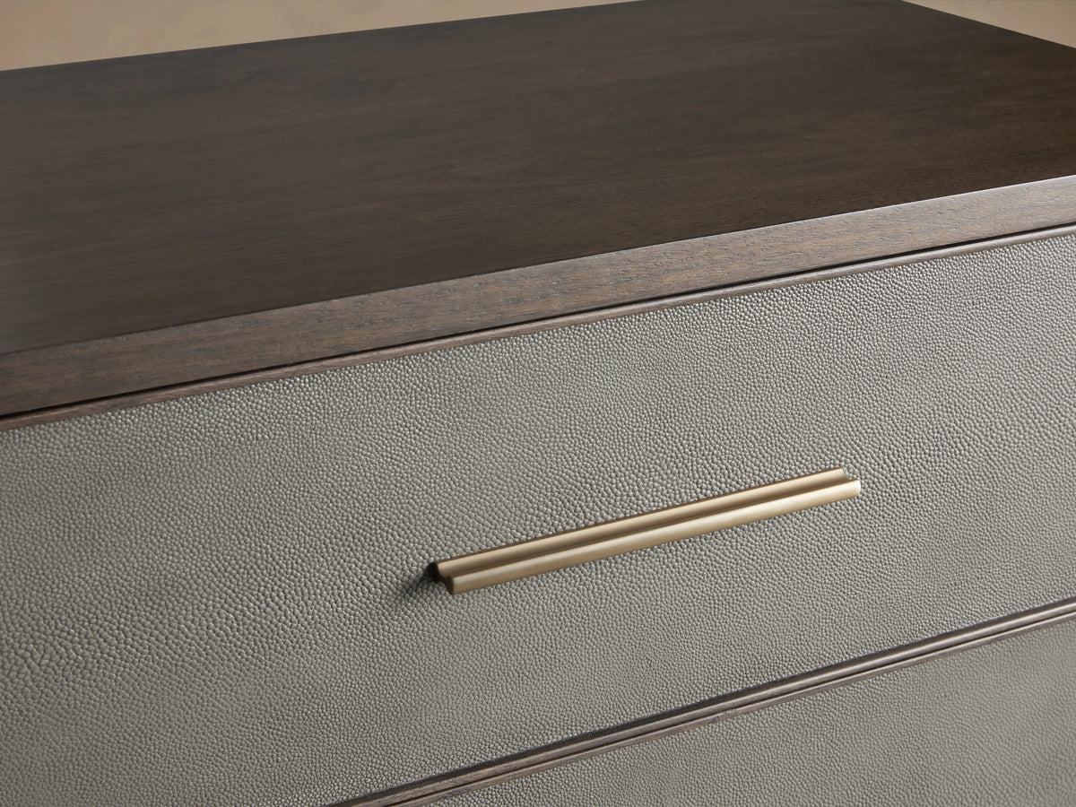 Malone Three-Drawer Chest with dark wood frame, gray leather insets, and brass handles and legs on a beige background.