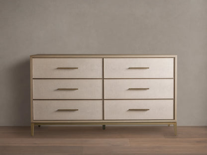 Front view of the Bone Malone Six-Drawer Dresser, featuring light beige textured shagreen drawer fronts, gold bar pulls, and tapered gold legs.