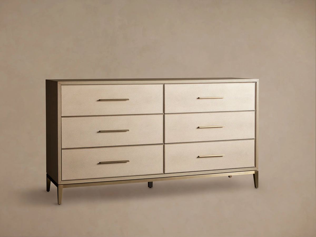 Front view of the Bone Malone Six-Drawer Dresser, featuring light beige textured shagreen drawer fronts, gold bar pulls, and tapered gold legs.