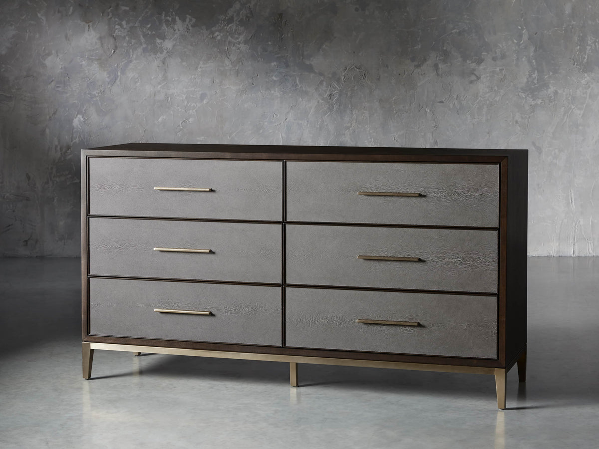 Front view of the Malone Six-Drawer Dresser, dark wood frame, six gray shagreen drawers, and warm metallic pulls and base.