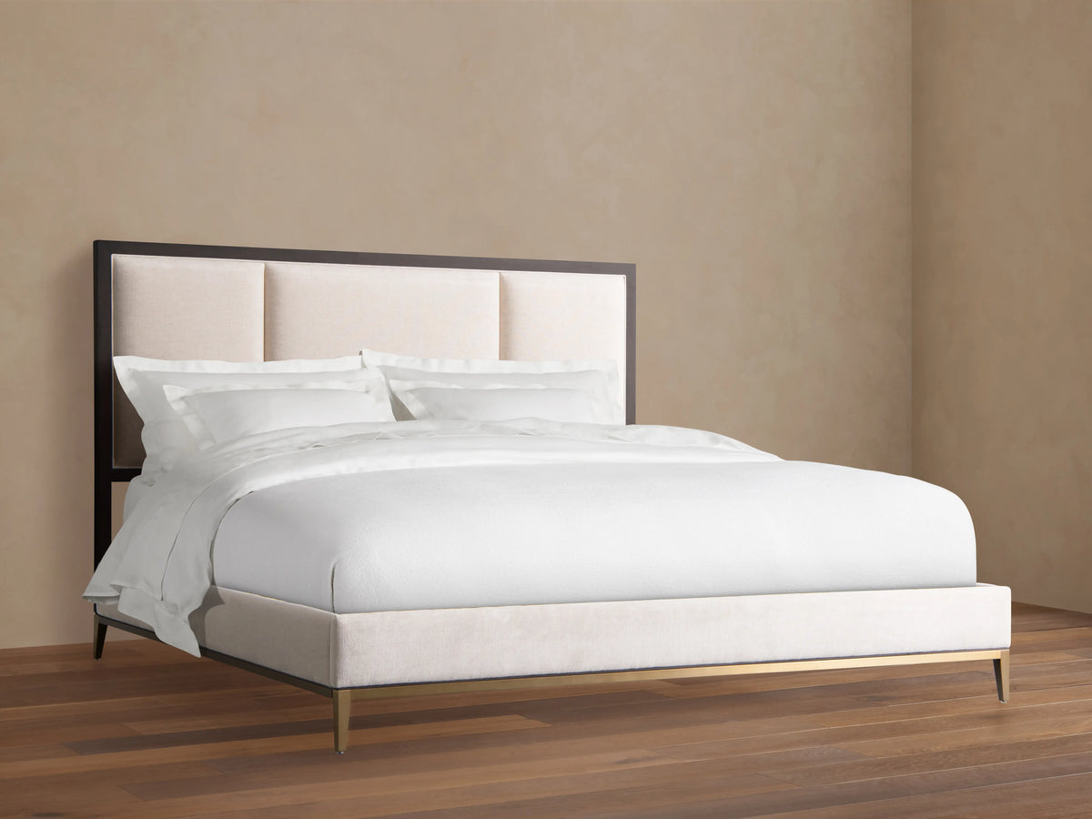 Malone Upholstered Bed with a neutral-toned headboard featuring three channel-stitched panels. Frame in dark wood, set in a spacious room.