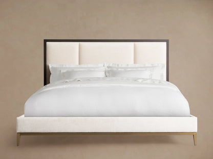 Malone Upholstered Bed with a neutral-toned headboard featuring three channel-stitched panels. Frame in dark wood, set in a spacious room.
