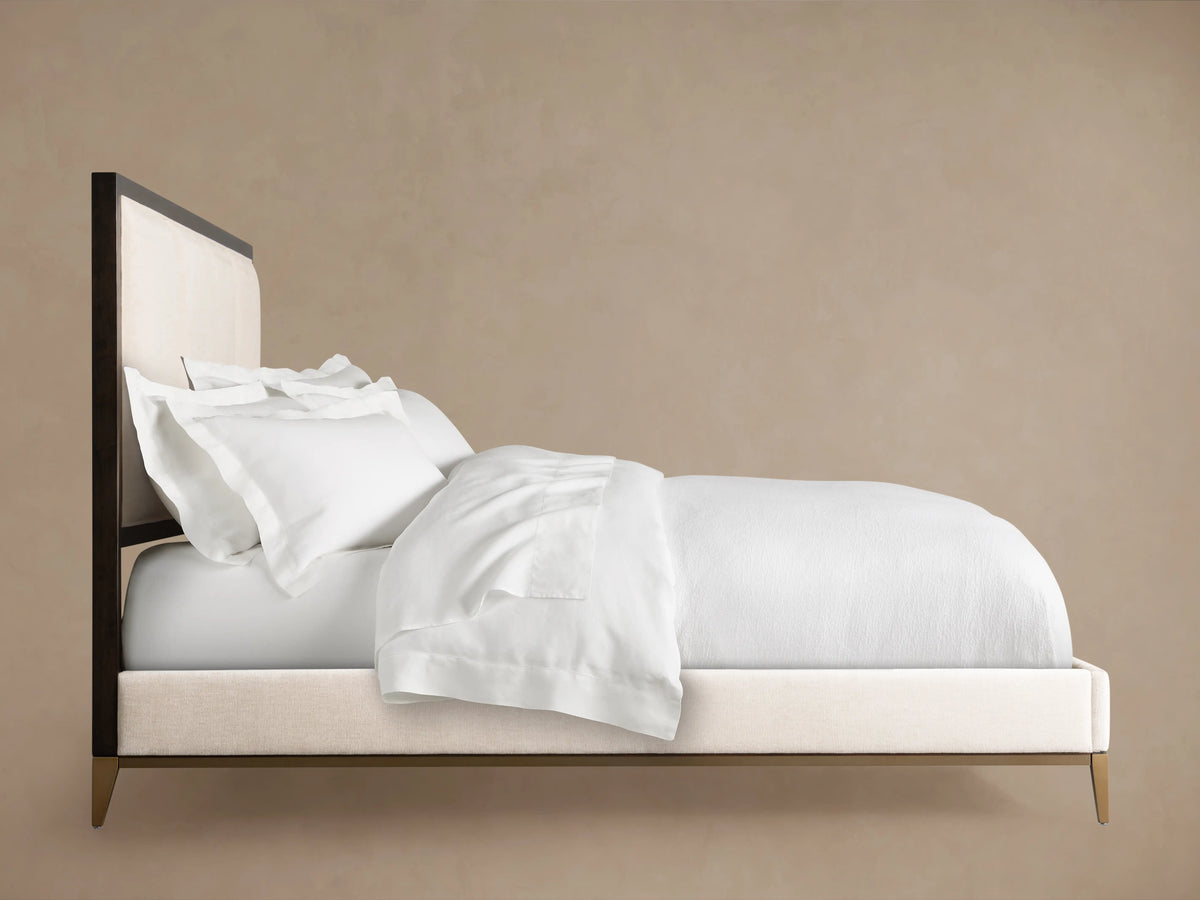 Upholstered headboard of Malone Bed with neutral fabric, framed by dark wood, showcasing channel-stitched detail.