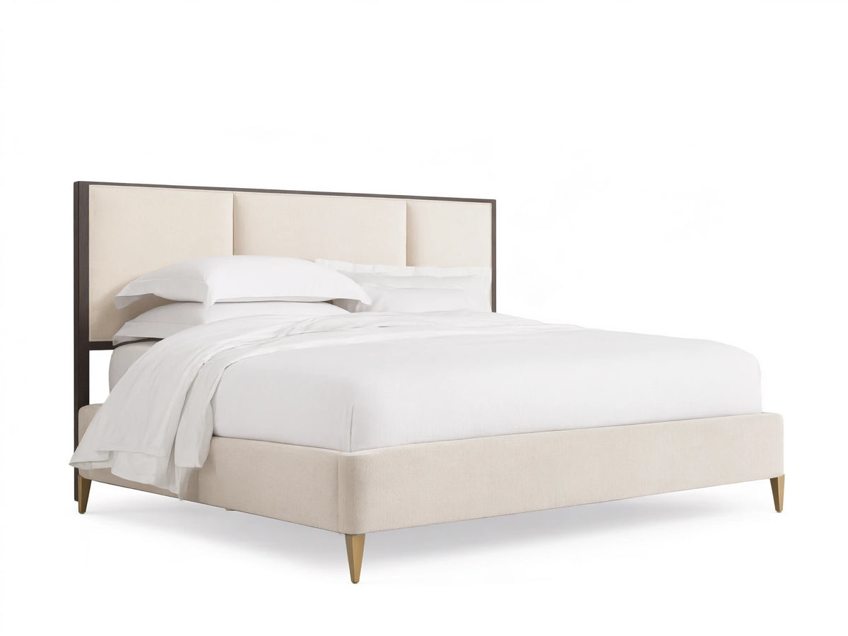 Malone Upholstered Bed with a neutral-toned headboard featuring three channel-stitched panels. Frame in dark wood, set in a spacious room.