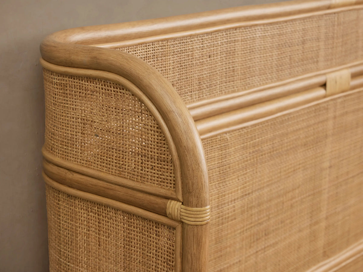 Maya Bed: light brown woven rattan mesh and bent cane frame, featuring a tall headboard, footboard, and white textured bedding.