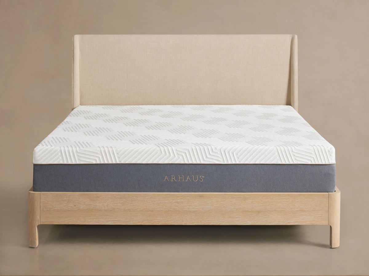 Memory foam plush mattress on a light wooden bed frame, featuring a white patterned surface and a gray base, in a minimalist bedroom.