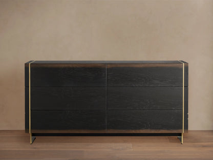 Mihaela Six-Drawer Dresser in dark oak with six drawers, featuring metallic brass accents on the edges, against a beige wall.