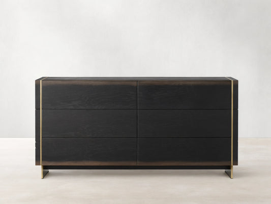 Mihaela Six-Drawer Dresser in dark oak with six drawers, featuring metallic brass accents on the edges, against a beige wall.
