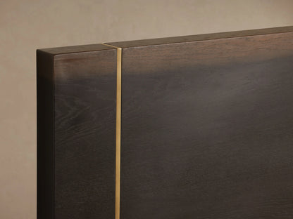 Mihaela Bed in dark Romanian oak with metallic brass accents, shown with white bedding against a beige background.