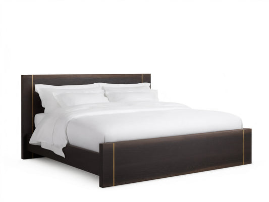 Mihaela Bed with dark oak frame, metallic brass accents, white bedding, on a wooden floor, set against a beige wall.